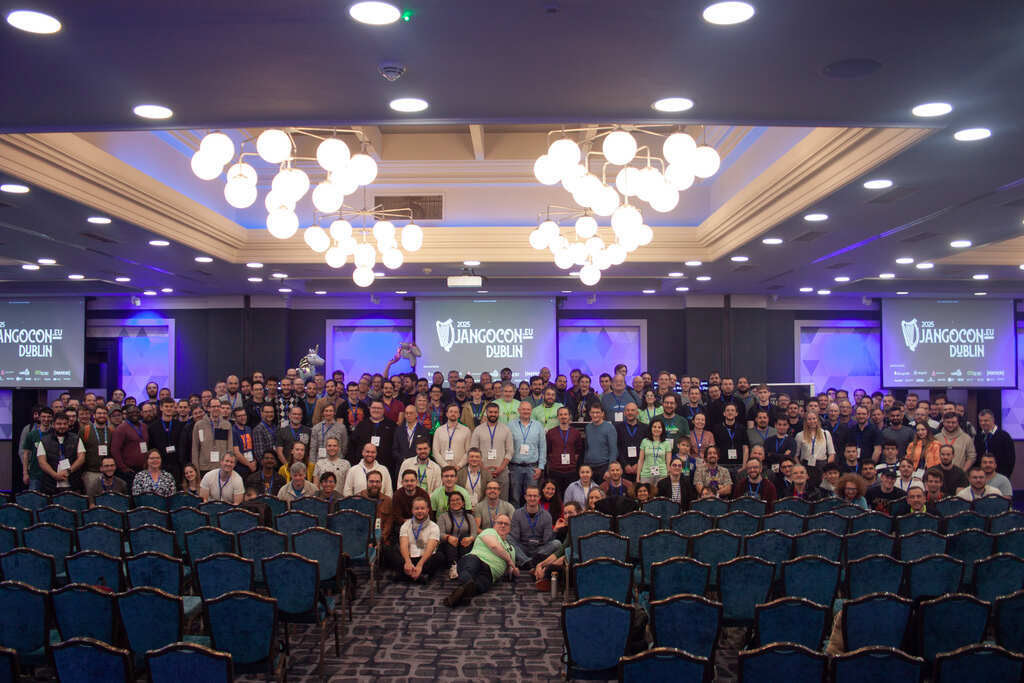 Group photo with all in-person DjangoCon Europe 2025 attendees, in a large conference room