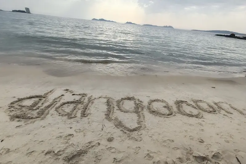 DjangoCon written in the sand on a beach, with the sea in the background