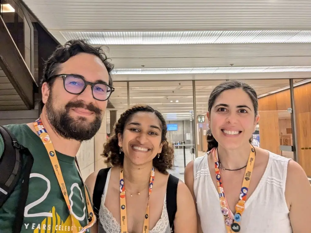 Paolo, Sarah, Çağıl taking a selfie with EuroPython 2024 lanyards on, smiling at the camera