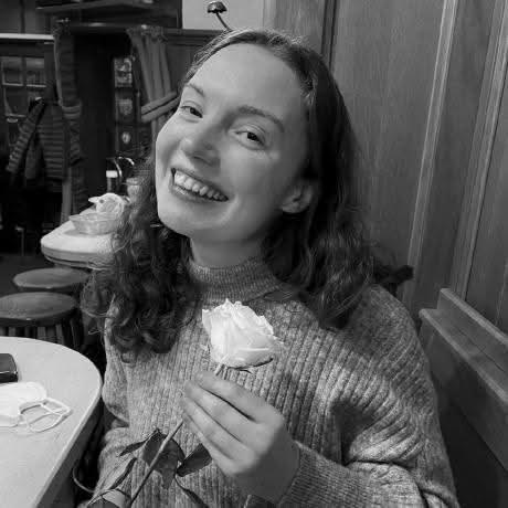 Black and white photo of Sarah, smiling, holding a flower